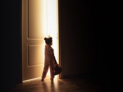 Little girl opens the door to the light in darkness