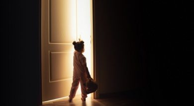 Little girl opens the door to the light in darkness