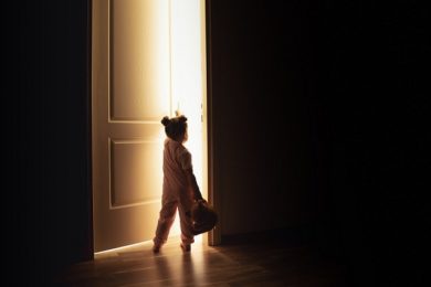 Little girl opens the door to the light in darkness